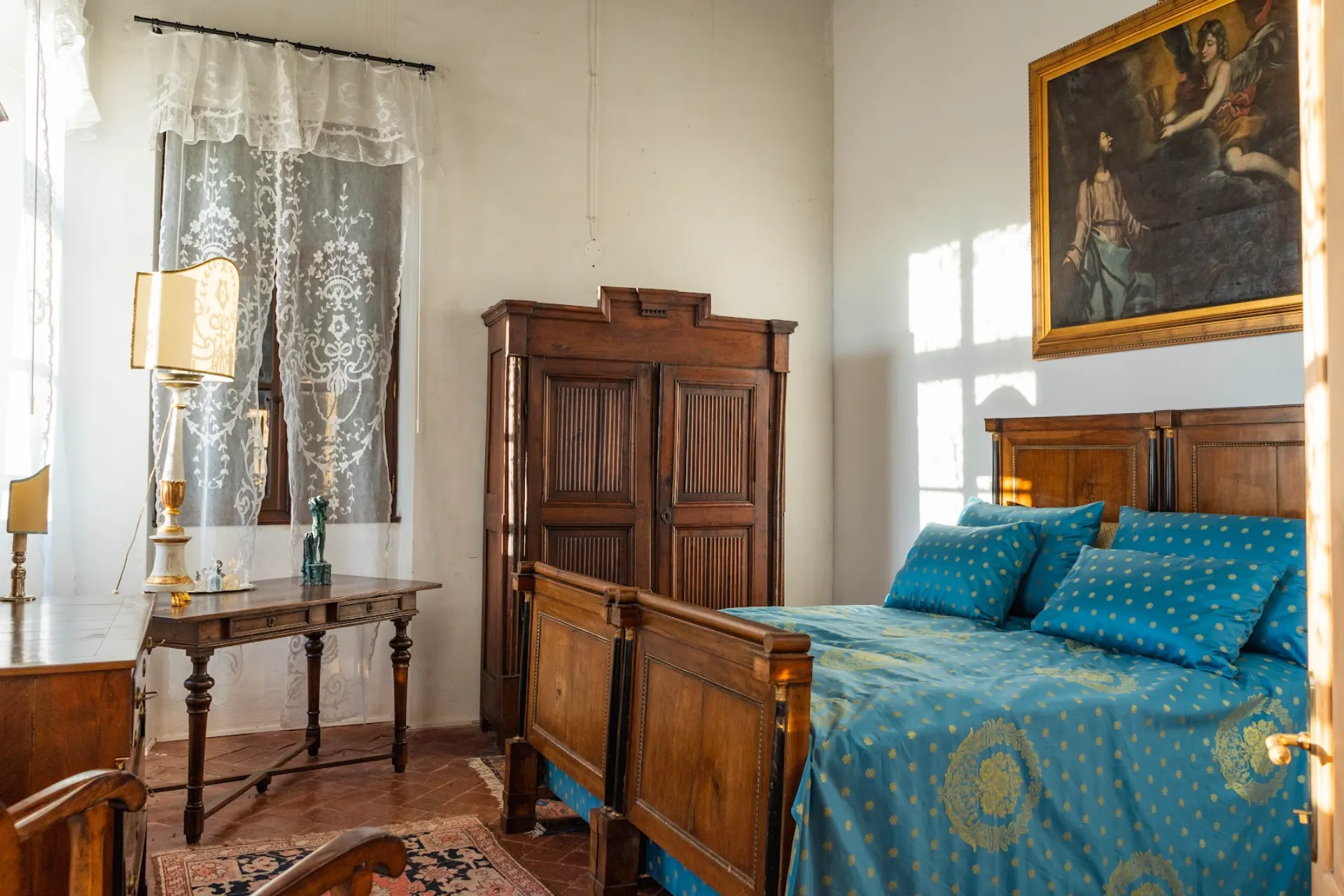 Elegant master bedroom in blue tones with antique wardrobe and period painting at Villa Ottelio