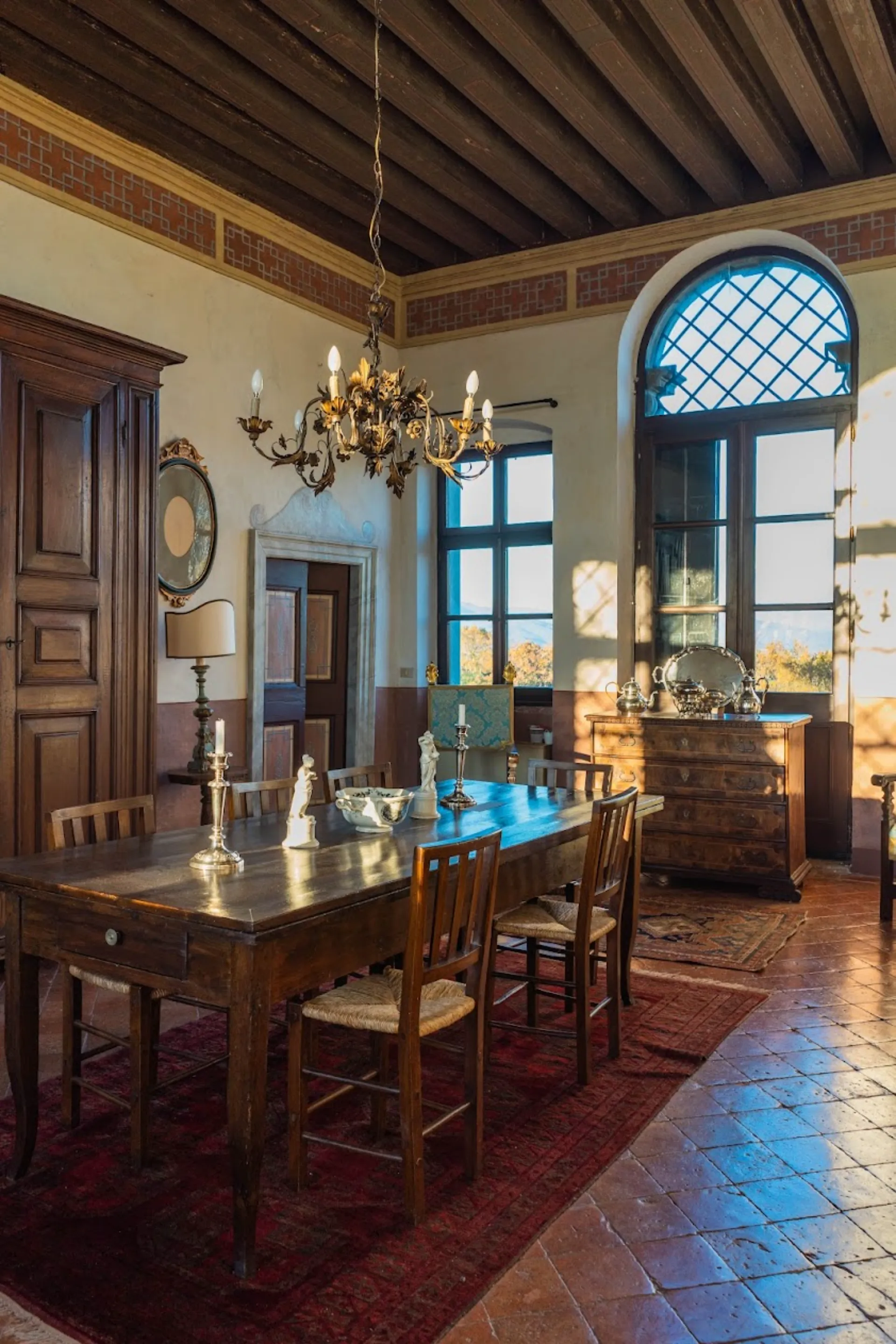 Bright central hall of Villa Ottelio with historical silverware and large arched windows