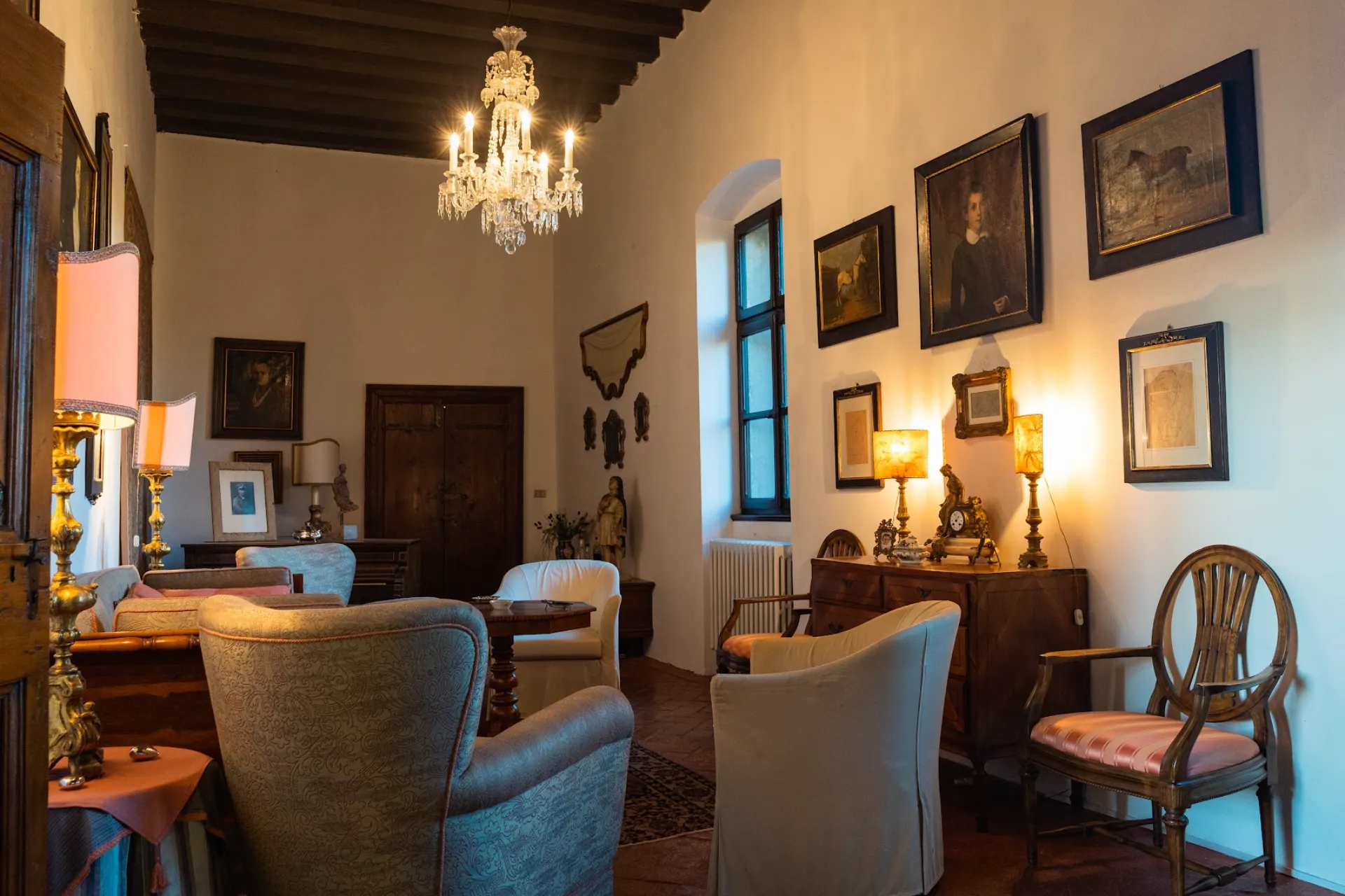 Historic sitting room of Villa Ottelio with antique portraits, period furniture, and a fine chandelier