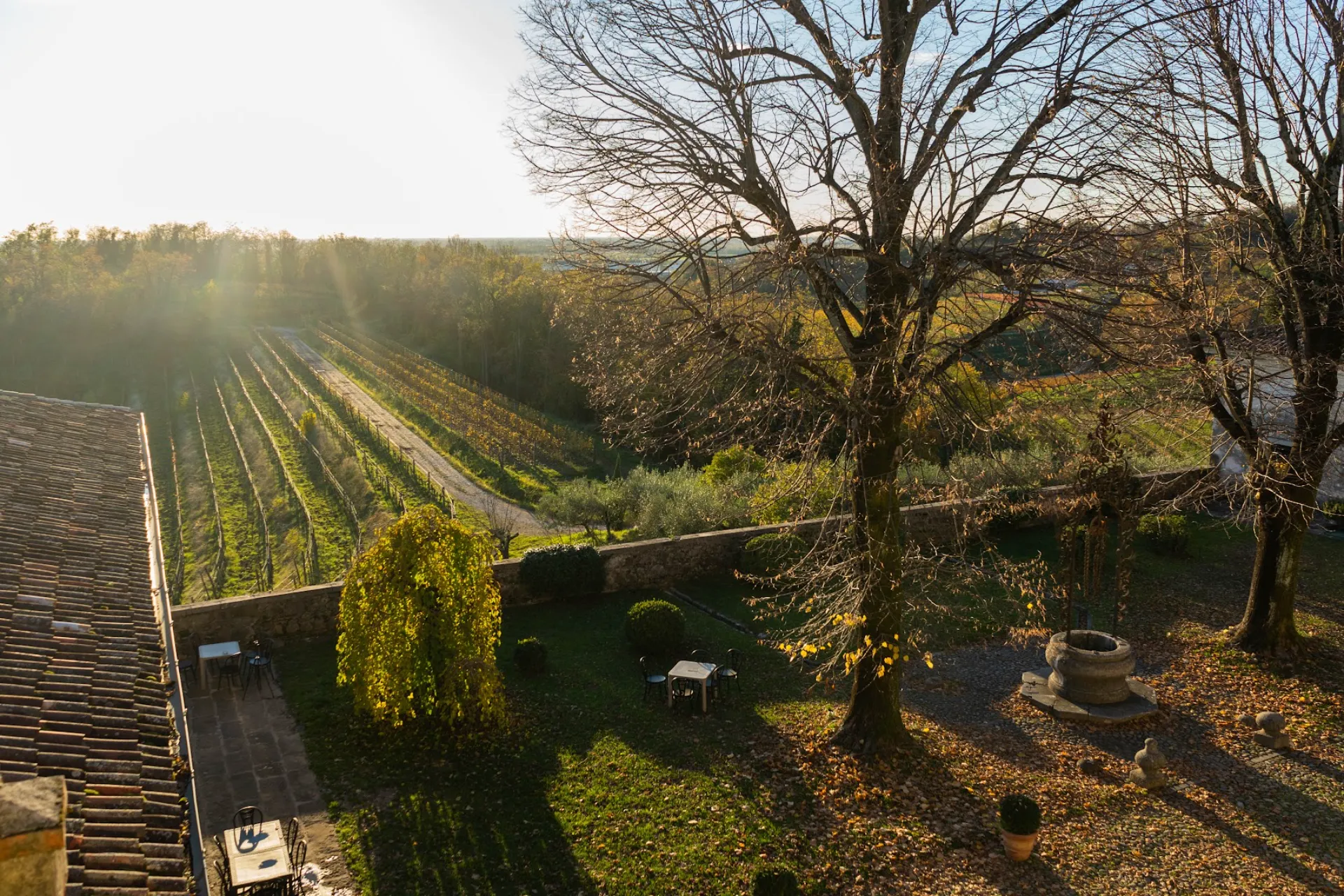 The historic well in Villa Ottelio's garden with an autumnal panoramic view of the vineyards
